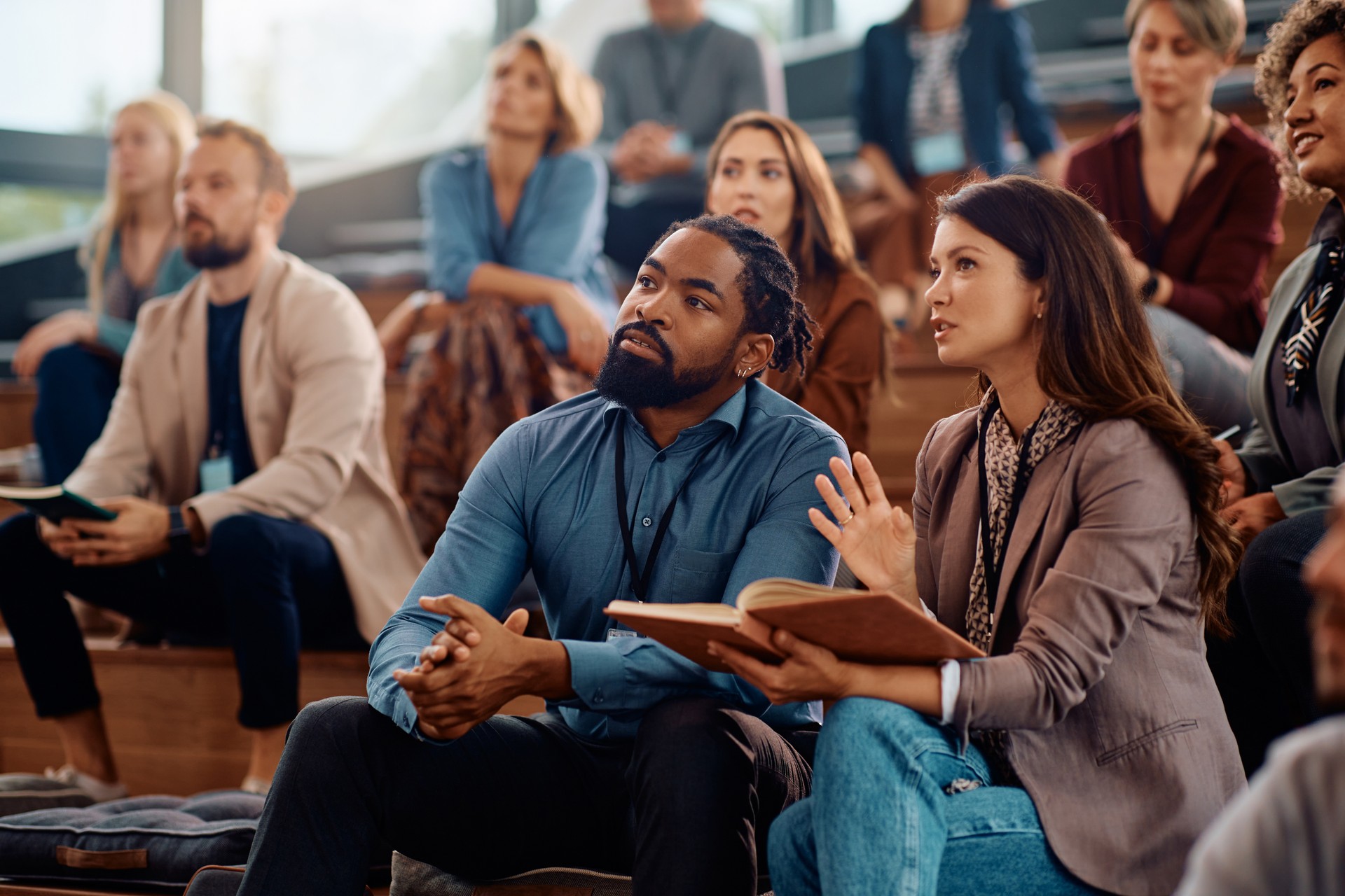 Business colleagues communicating during a seminar in conference hall.
