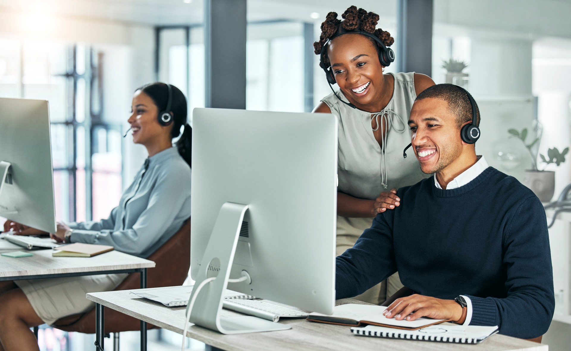 Support, training and coaching, a call center manager is happy to help her team. Collaboration, leadership and teamwork at a tech startup. Office diversity, young men and women working with computers