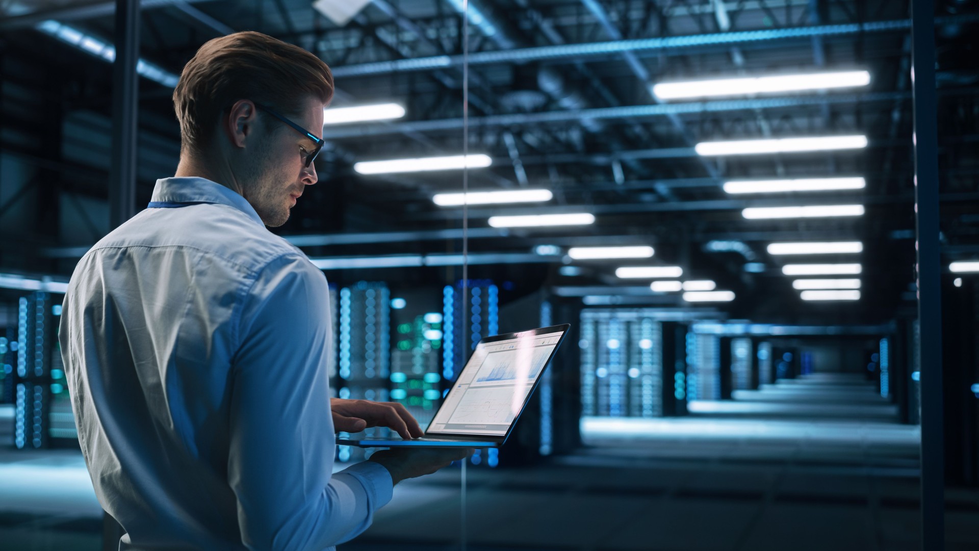 Data Center Male It Specialist Using Laptop while Working on Computer. Information Technology Professional. Server Farm Cloud Computing and Cyber Security Maintenance Concept